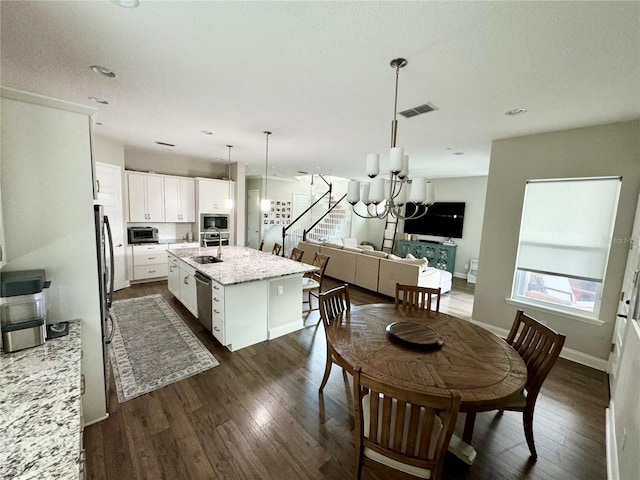 dining area featuring baseboards, dark wood-style flooring, visible vents, and a notable chandelier