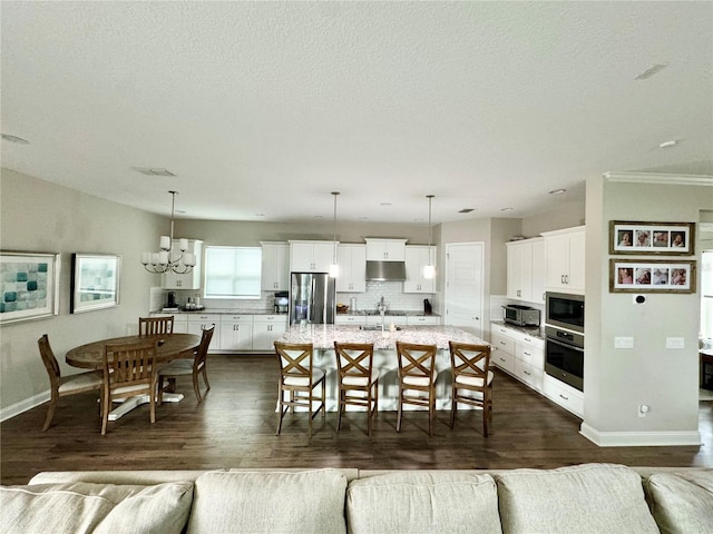 living room featuring a chandelier, dark wood-style flooring, a textured ceiling, and baseboards