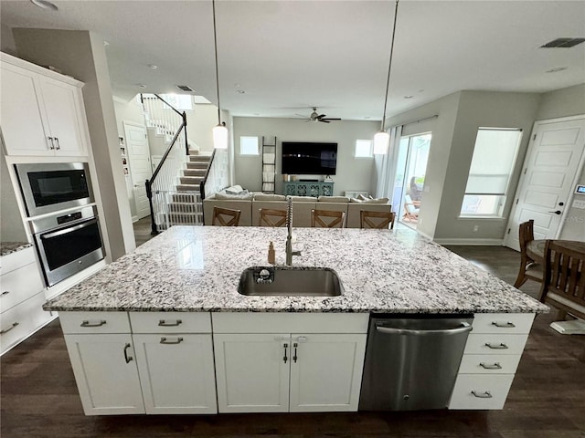 kitchen with visible vents, appliances with stainless steel finishes, open floor plan, a kitchen island with sink, and a sink