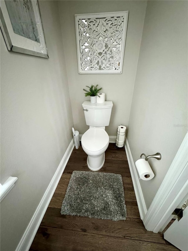 bathroom featuring toilet, baseboards, and wood finished floors