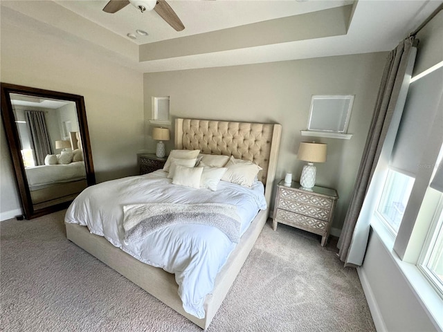 bedroom featuring a raised ceiling, carpet flooring, and baseboards