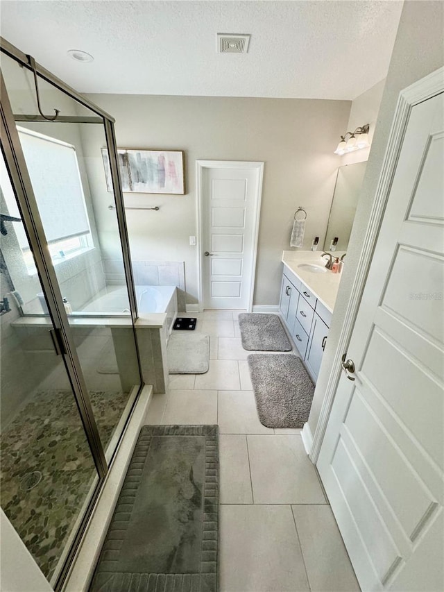 bathroom with tile patterned flooring, vanity, a textured ceiling, and a bath