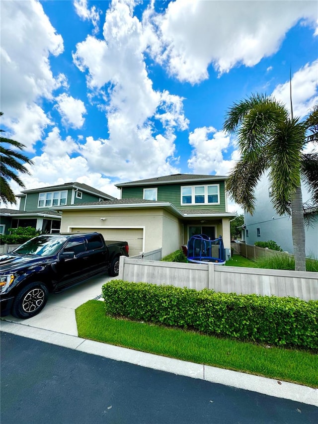 view of front of house with an attached garage, fence, and concrete driveway