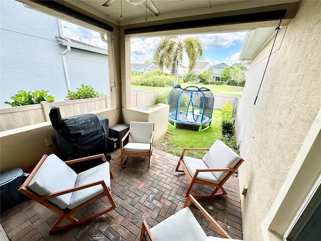 exterior space with ceiling fan, a trampoline, a grill, and fence