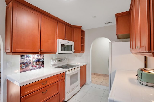 44 Capistrano Dr, Ormond Beach, FL 32176 - kitchen with white appliances, visible vents, arched walkways, open shelves, and backsplash