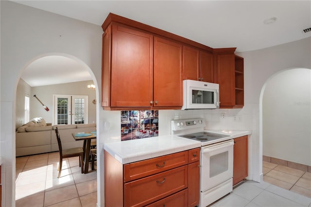 44 Capistrano Dr, Ormond Beach, FL 32176 - kitchen with white appliances, tasteful backsplash, light tile patterned floors, arched walkways, and lofted ceiling