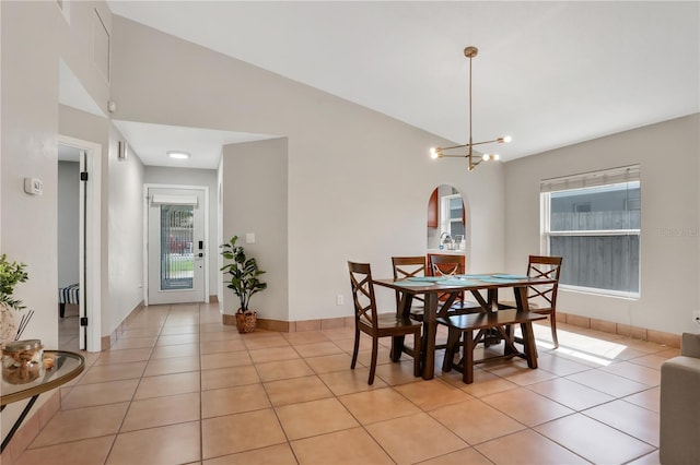 44 Capistrano Dr, Ormond Beach, FL 32176 - dining area with light tile patterned floors, baseboards, arched walkways, lofted ceiling, and a notable chandelier