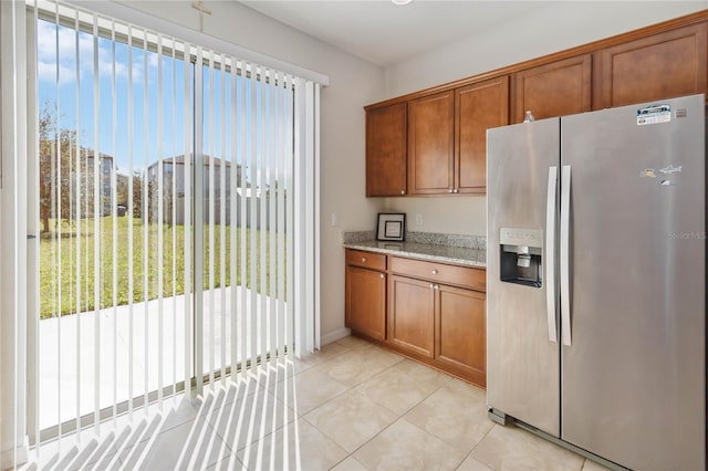 kitchen with brown cabinetry, a wealth of natural light, and stainless steel fridge with ice dispenser