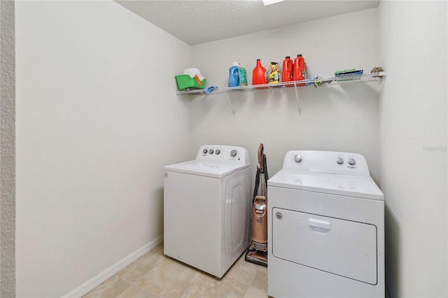 laundry room with laundry area, light tile patterned flooring, washing machine and clothes dryer, and baseboards