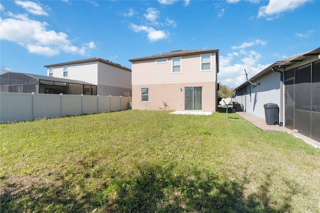 rear view of house with a lawn and fence