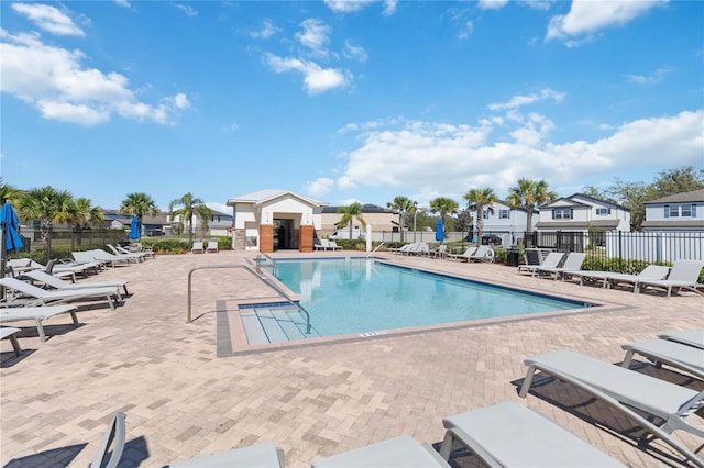 community pool with a patio area, fence, and a residential view