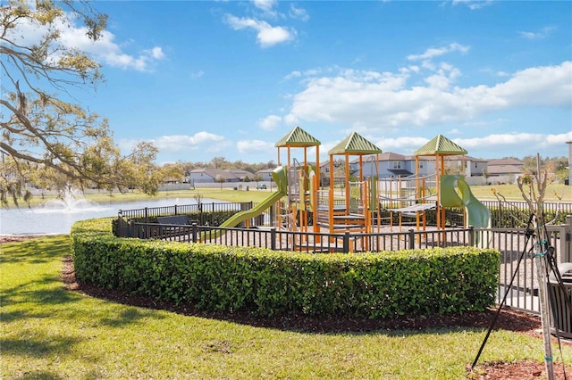 community playground with a yard, a water view, and fence