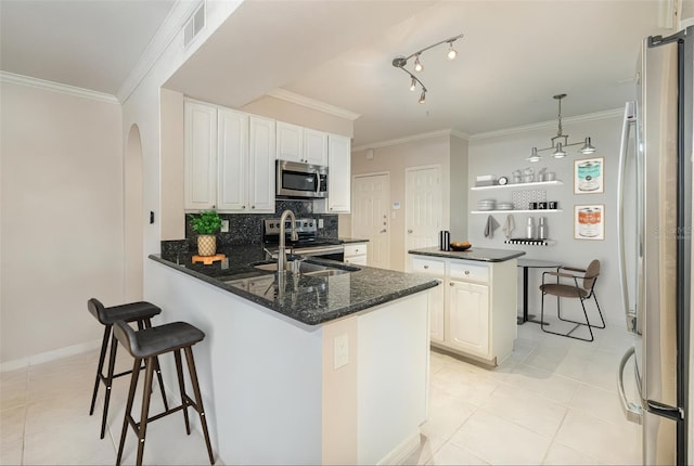 kitchen with arched walkways, stainless steel appliances, visible vents, ornamental molding, and a peninsula