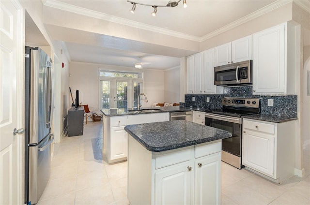 kitchen with stainless steel appliances, a peninsula, a sink, ornamental molding, and tasteful backsplash