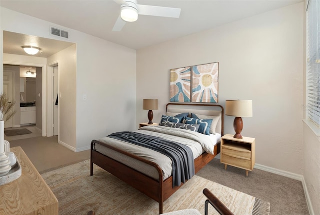 carpeted bedroom with a ceiling fan, ensuite bath, visible vents, and baseboards