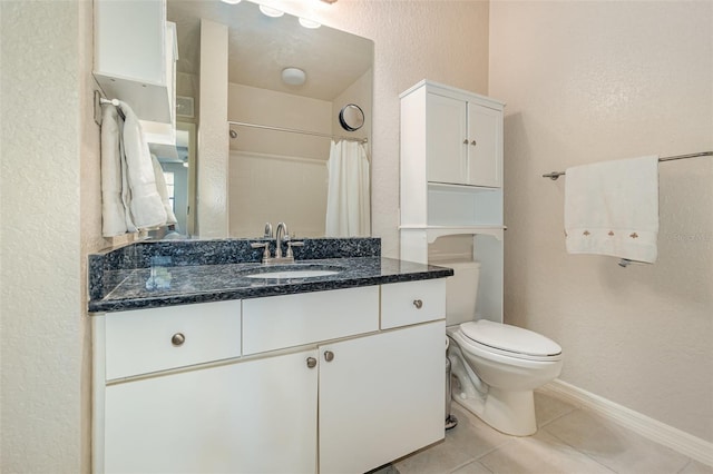 bathroom featuring a textured wall, toilet, vanity, baseboards, and tile patterned floors