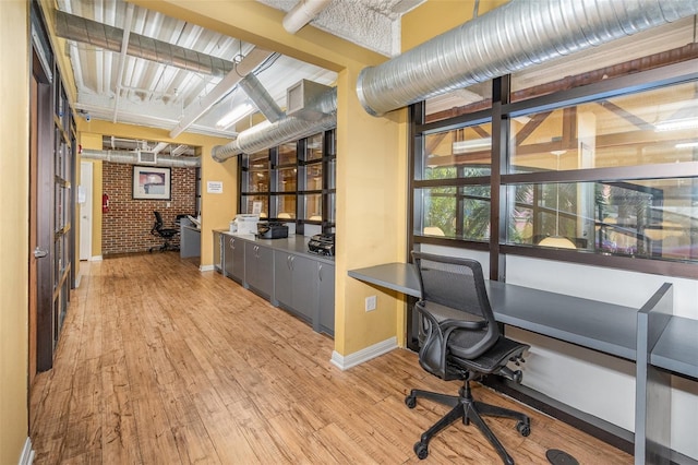 office area with light wood-type flooring, baseboards, and built in study area