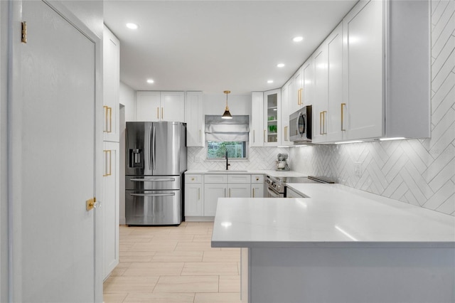 kitchen with light countertops, backsplash, appliances with stainless steel finishes, white cabinetry, and a sink