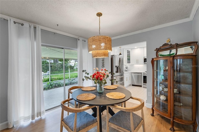 dining area featuring light wood-type flooring, a textured ceiling, baseboards, and crown molding