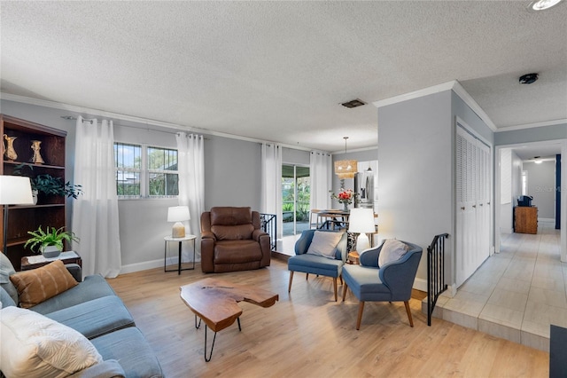 living area with baseboards, visible vents, ornamental molding, a textured ceiling, and light wood-style floors