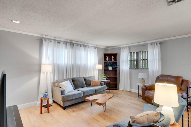 living area with light wood-style floors, ornamental molding, and a textured ceiling