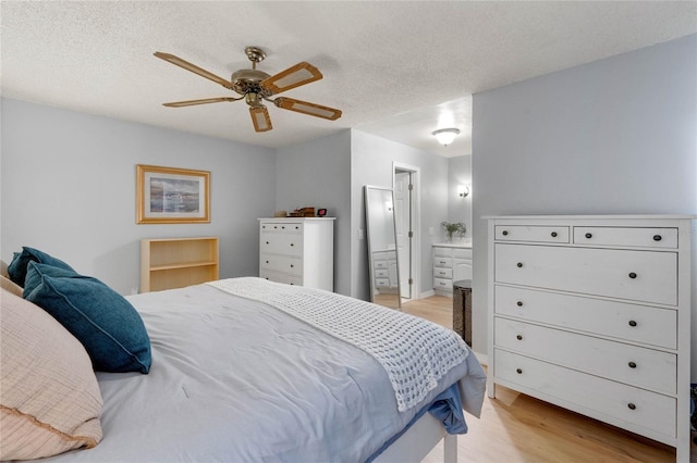 bedroom with light wood-type flooring, connected bathroom, a ceiling fan, and a textured ceiling