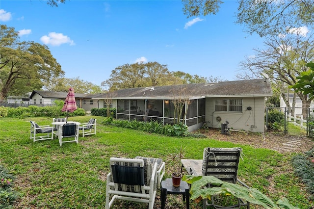 rear view of house with a yard, fence, and a sunroom