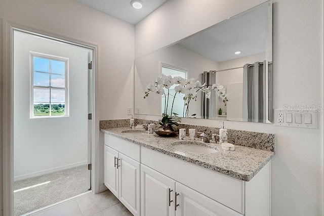 full bath featuring tile patterned floors, a sink, baseboards, and double vanity