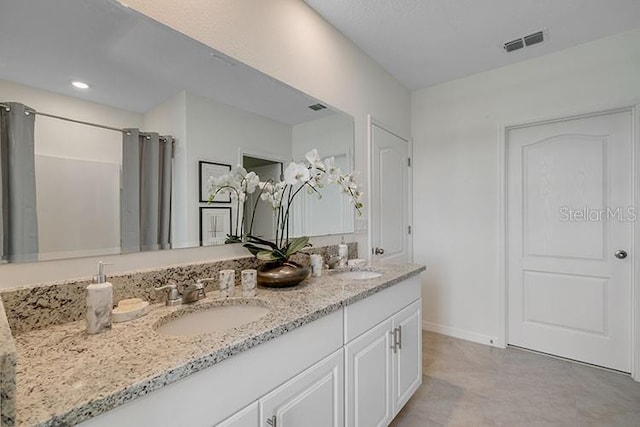 bathroom with visible vents, a sink, baseboards, and double vanity