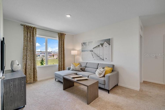 living room featuring light colored carpet, a textured ceiling, and baseboards