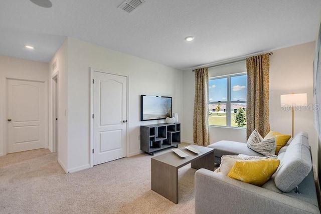 living area with light colored carpet, visible vents, a textured ceiling, and baseboards