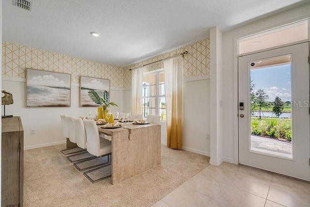 dining space featuring a healthy amount of sunlight, visible vents, baseboards, and wallpapered walls