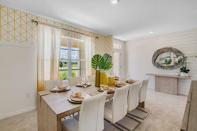 dining room featuring light carpet, a textured ceiling, and baseboards