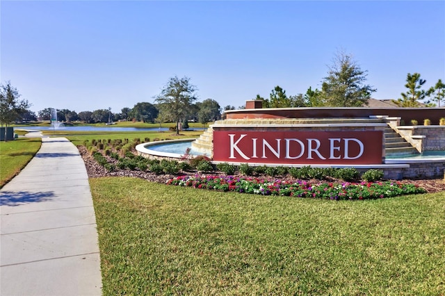 community sign with a water view and a yard