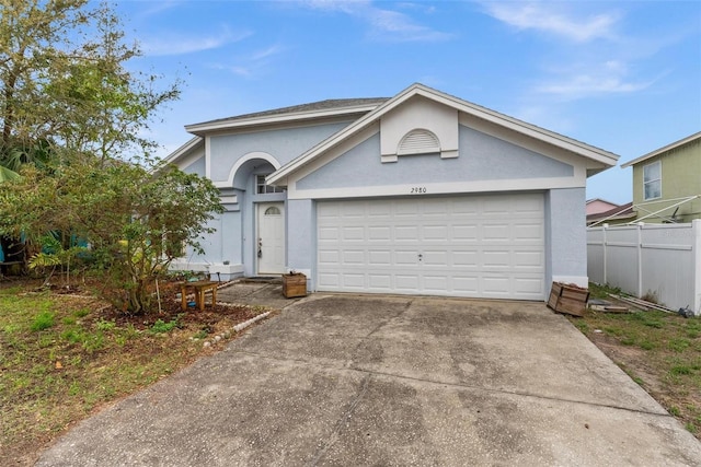 single story home featuring an attached garage, fence, concrete driveway, and stucco siding