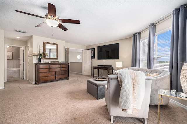 carpeted living area with visible vents, ceiling fan, and a textured ceiling