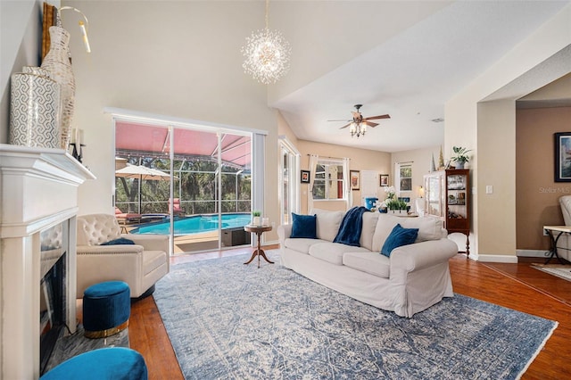 living room featuring a sunroom, ceiling fan, baseboards, and wood finished floors