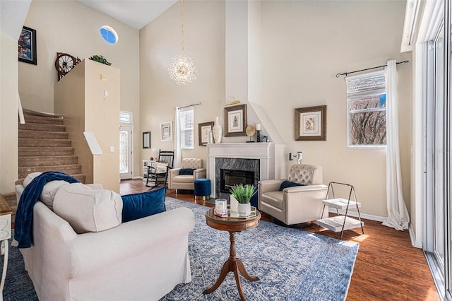 living area featuring a high end fireplace, baseboards, stairway, dark wood finished floors, and an inviting chandelier