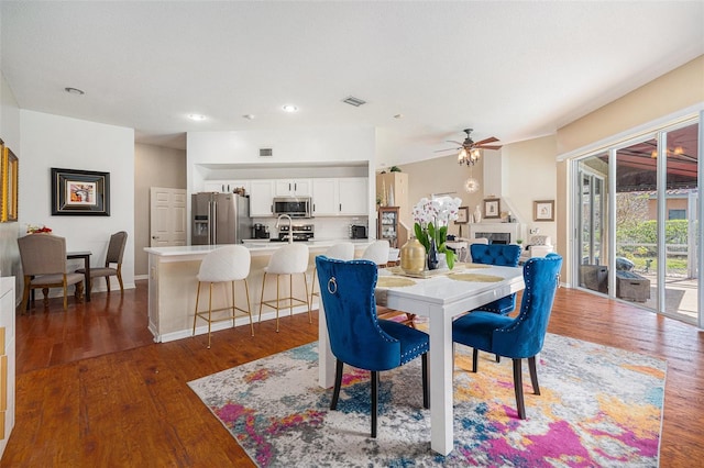 dining area with baseboards, visible vents, wood finished floors, and a glass covered fireplace