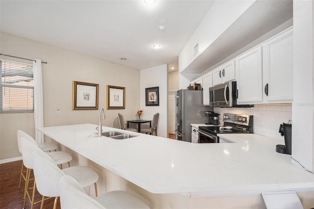 kitchen featuring dark wood finished floors, tasteful backsplash, appliances with stainless steel finishes, white cabinetry, and a sink