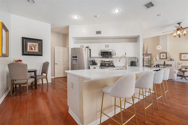 kitchen with a breakfast bar, stainless steel appliances, visible vents, backsplash, and a sink