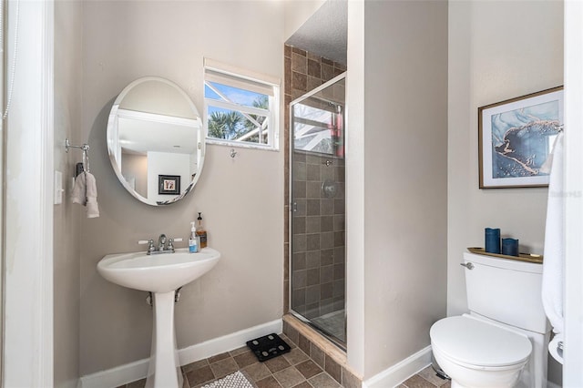 full bathroom featuring toilet, a shower stall, and baseboards