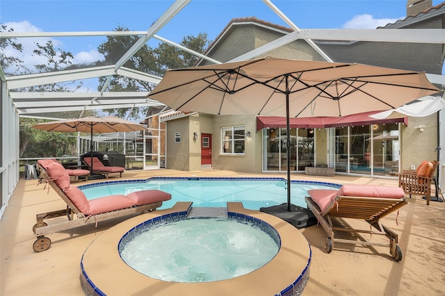 view of pool with a pool with connected hot tub, glass enclosure, and a patio