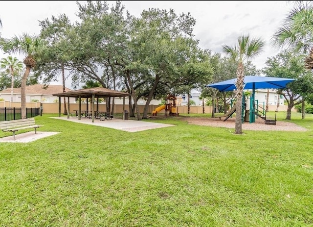 view of property's community with playground community, a lawn, a gazebo, and fence