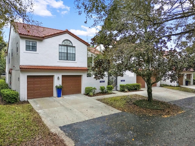 mediterranean / spanish-style house with driveway, an attached garage, a tiled roof, and stucco siding