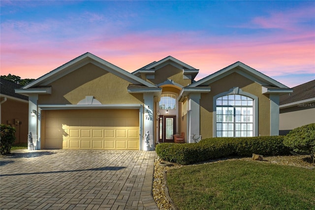 ranch-style house featuring a garage, decorative driveway, and stucco siding