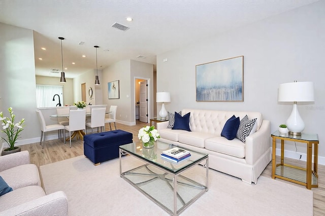 living room featuring light wood finished floors, baseboards, visible vents, and recessed lighting