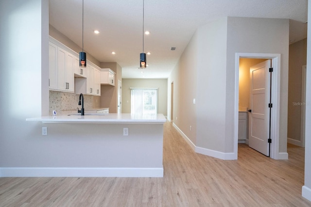 kitchen featuring light countertops, a sink, light wood-style flooring, and white cabinetry