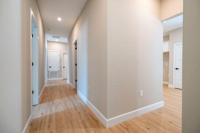 hallway with light wood-type flooring, visible vents, and baseboards