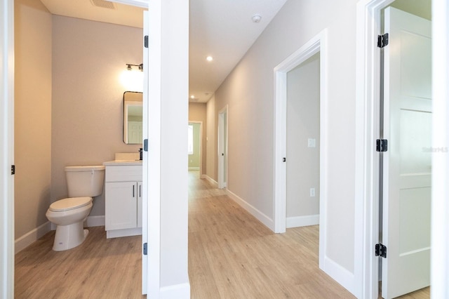 hallway with recessed lighting, visible vents, light wood-style flooring, and baseboards